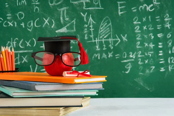 Elma bilgi sembolü ve masanın üstüne kalem kitap