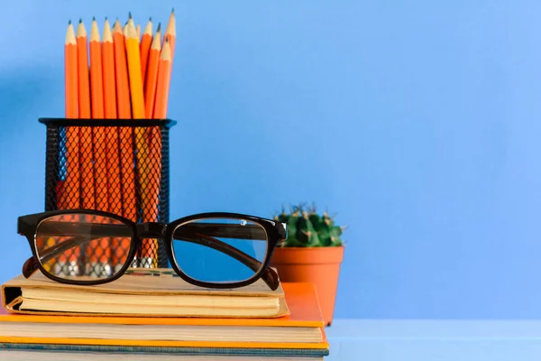Книги Олівець і окуляри на синьому дерев'яному столі — стокове фото