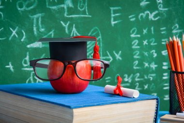 Elma bilgi sembolü ve masanın üstüne kalem kitap 