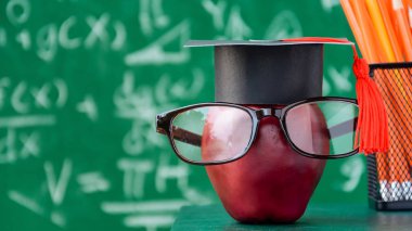 Elma bilgi sembolü ve masanın üstüne kalem kitap