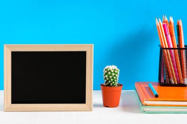 Ahşap masa üzerinde çerçeve ve kitap kalem kadar sahte ile yazı tahtası