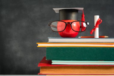 Elma bilgi sembolü ve masanın üstüne kalem kitap