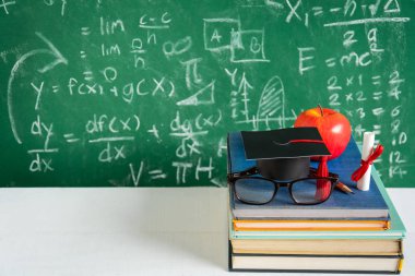 Elma bilgi sembolü ve masanın üstüne kalem kitap