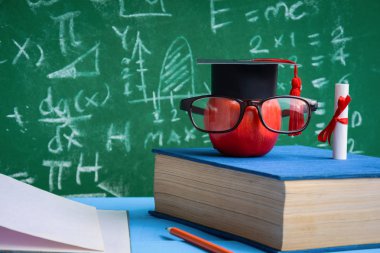 Elma bilgi sembolü ve masanın üstüne kalem kitap 