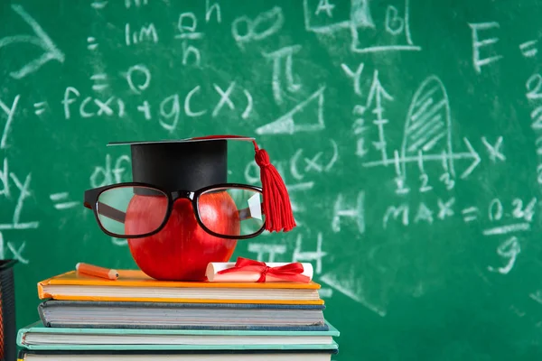 Elma bilgi sembolü ve masanın üstüne kalem kitap