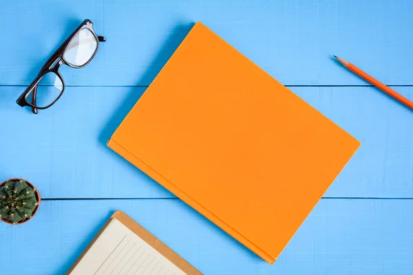 Vista superior libro maqueta y lápiz nota sobre tabla de madera azul — Foto de Stock