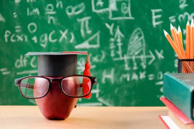 Elma bilgi sembolü ve masanın üstüne kalem kitap