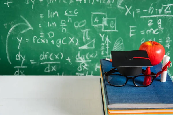 Elma bilgi sembolü ve masanın üstüne kalem kitap