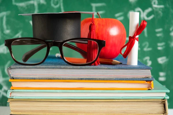 Elma bilgi sembolü ve masanın üstüne kalem kitap