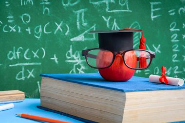 Elma bilgi sembolü ve masanın üstüne kalem kitap 