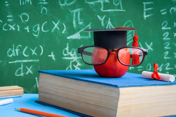 Elma bilgi sembolü ve masanın üstüne kalem kitap 