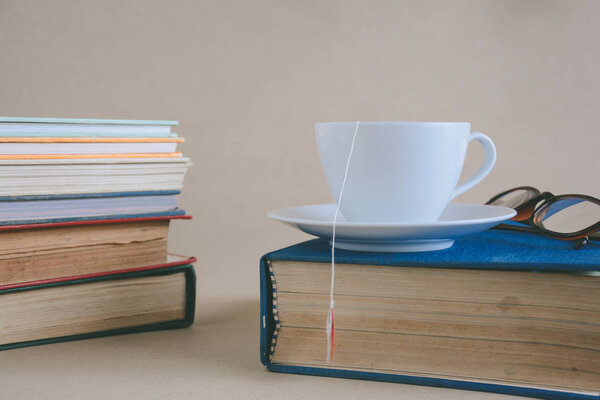 Book glasses and tea on the desk with study and education concep