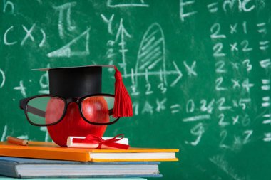 Elma bilgi sembolü ve masanın üstüne kalem kitap