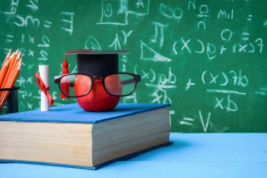 Elma bilgi sembolü ve masanın üstüne kalem kitap 