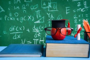 Elma bilgi sembolü ve masanın üstüne kalem kitap 