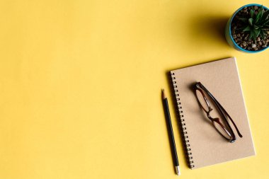 defter ve kalem sarı masa üzerinde