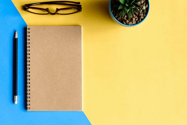 Cuaderno y lápiz sobre escritorio amarillo — Foto de Stock