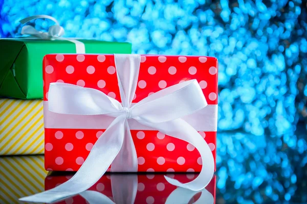 Cadeaux et jouets sur table en verre et fond de lumière bleu bokeh — Photo