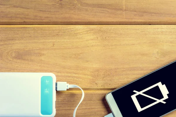 stock image top view charge the smartphone on a wooden table.