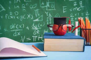 Elma bilgi sembolü ve masanın üstüne kalem kitap 