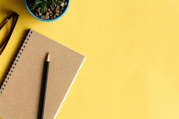 Cuaderno y lápiz sobre escritorio amarillo — Foto de Stock