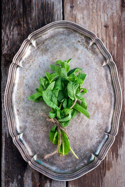 A fresh bunch of mint on a vintage tray, top view, selective focus