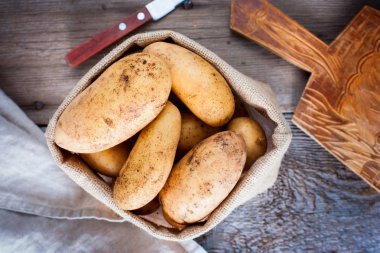 Bir torbaya bir ahşap masa, üstten görünüm, seçici odak taze genç patates