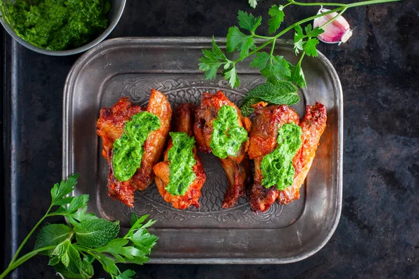 Tavuk kanatları-ızgara nane ve maydanoz, üstten görünüm, yatay pesto ile metal bir plaka üzerinde