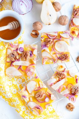 Pizza bir armut ve soğan ile parçalar halinde kesilmiş bir beyaz standı, üstten görünüm, seçici odak