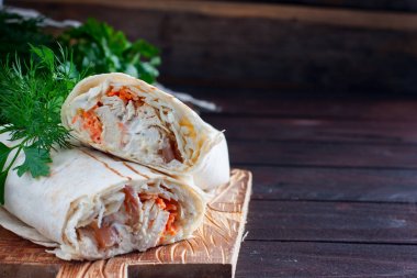 Tavuk rulo shawarma pide taze sebze ile ahşap bir arka plan üzerinde. Uzay kopyalayın. Yatay görüntü