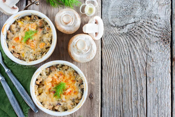 Warm voorgerecht (Julienne) met champignons, prei, kaas en dille in porselein keramische vormen op een houten tafel, bovenaanzicht, kopie ruimte — Stockfoto