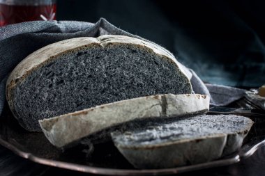 Gri bir peçete ile metal bir tepsi üzerinde siyah kömür ekmek doğranmış, yatay