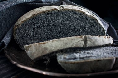 Gri bir peçete ile metal bir tepsi üzerinde siyah kömür ekmek doğranmış, yatay
