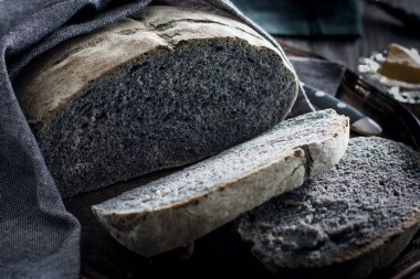 Gri bir peçete ile metal bir tepsi üzerinde siyah kömür ekmek doğranmış, yatay