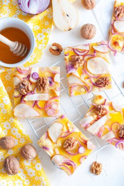 Pizza bir armut ve soğan ile parçalar halinde kesilmiş bir beyaz standı, üstten görünüm, seçici odak