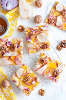 Pizza bir armut ve soğan ile parçalar halinde kesilmiş bir beyaz standı, üstten görünüm, seçici odak