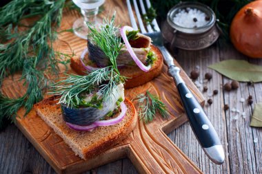 Soğan, seçici odak ile siyah ekmek üzerinde dereotu ile marine edilmiş ringa balığı