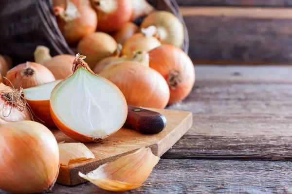 Vintage uien op een houten tafel met een gesneden ui op een bord, vitaminen, horizontaal, kopie ruimte — Stockfoto