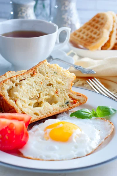 Fresh breakfast with scrambled eggs, fresh tomatoes and sliced pieces of muffins with mozzarella and sun-dried tomatoes, selective focus