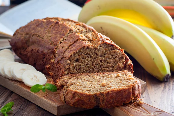 Bolo de banana fatiado com farinha de grãos integrais em uma placa de madeira, foco seletivo — Fotografia de Stock