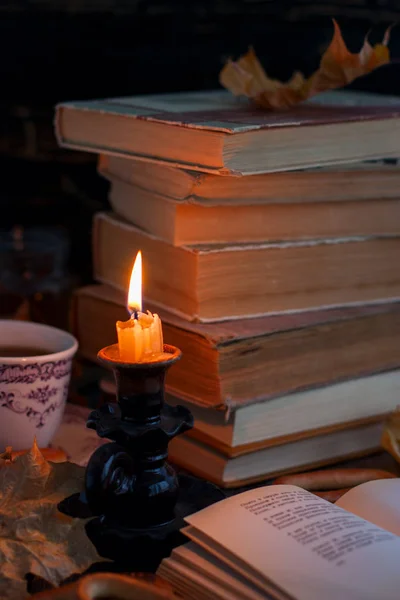 Stapel van oude gehavend boek over een houten tafel brandende kaars en bril — Stockfoto