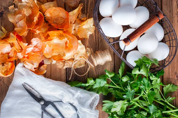 Cascas de cebola, ovos, tecido branco, tesoura, salsa fresca - preparação para tingir ovos para a Páscoa, vista superior — Fotografia de Stock