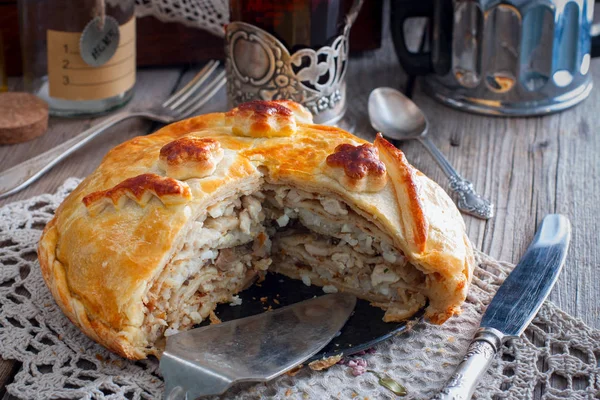 Festive national Russian pie from chicken, pancakes, rice, mushrooms. Cornice cut, selective focus