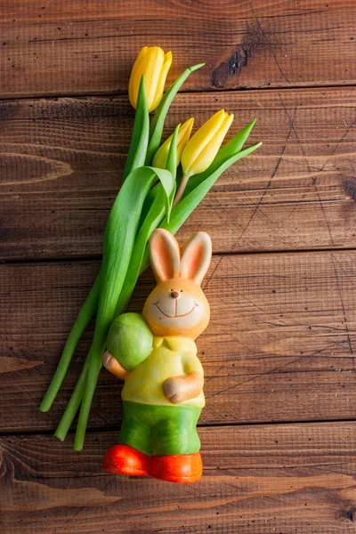 Celebratory tulips and elegant easter bunny on a wooden background, top view. Easter concept.