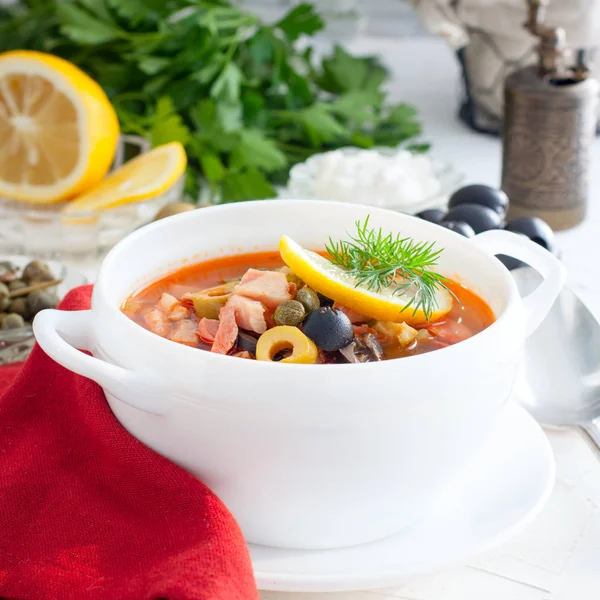 Hot Soup Solyanka with pickled cucumbers, olives, olives, capers, ham and lemon, square — Stock Photo, Image