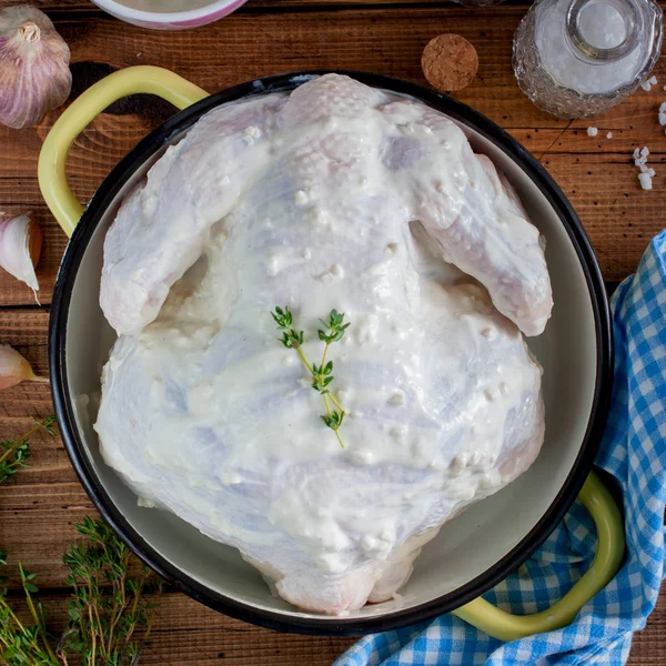 Raw whole chicken marinated with garlic, thyme and spices close-up on the table. Square — Stock Photo, Image