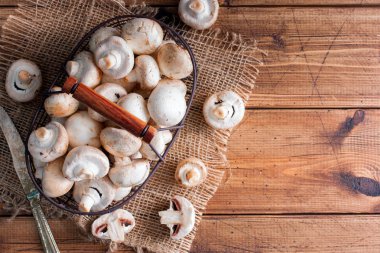 Üstten Görünüm, ahşap bir masa üzerinde metal bir sepet içinde ham taze mantar alanı Kopyala