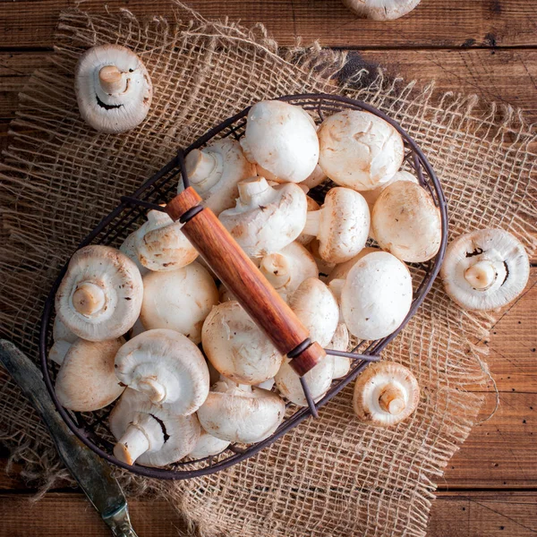 Rauwe verse champignons in een metalen mand op een houten tafel, bovenaanzicht — Stockfoto