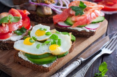 Bir açık sandviç avokado, Bıldırcın yumurta ve taze fesleğen Yeşiller lor peyniri, seçici odak ile siyah ekmek üzerinde