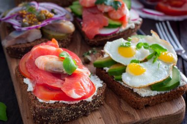 Kırmızı balık, karides, lor peyniri, seçici odak ile siyah ekmek üzerinde taze sebze ile bir açık sandviç